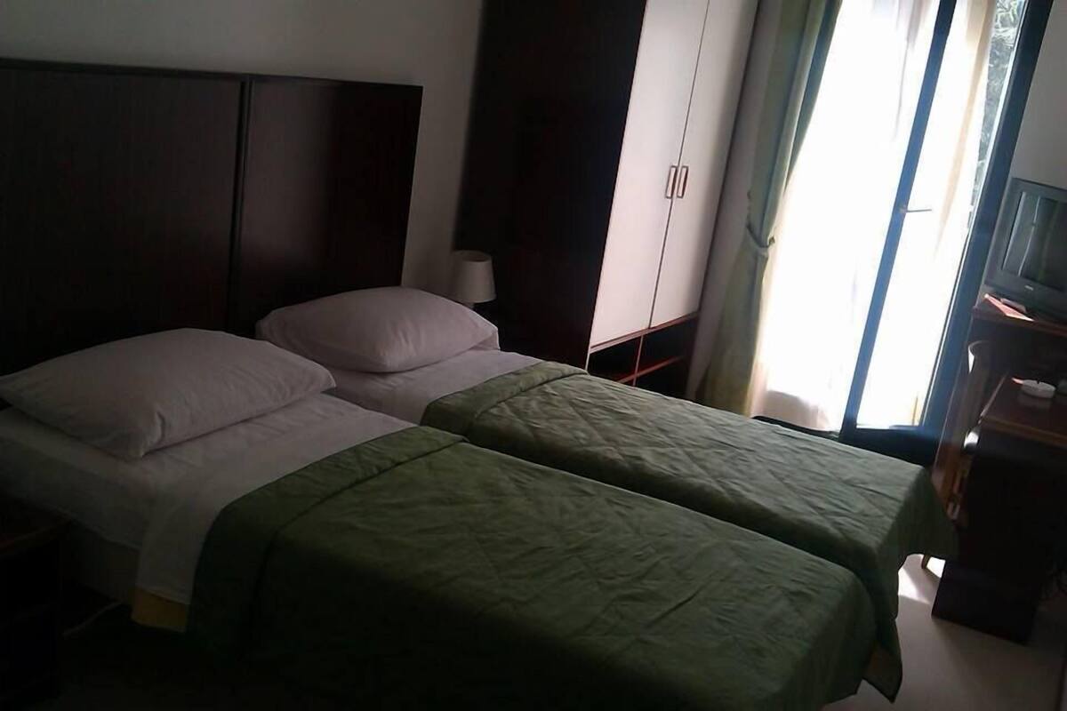 A room with two beds, a wardrobe, a desk, and a window.