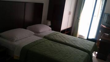 Ein Hotelzimmer mit zwei Betten, einem Kleiderschrank, einem Schreibtisch und einem Fenster.