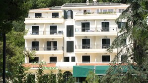 Un hotel de varios pisos con balcones, un toldo verde y un cartel que dice "HOTEL Danica".