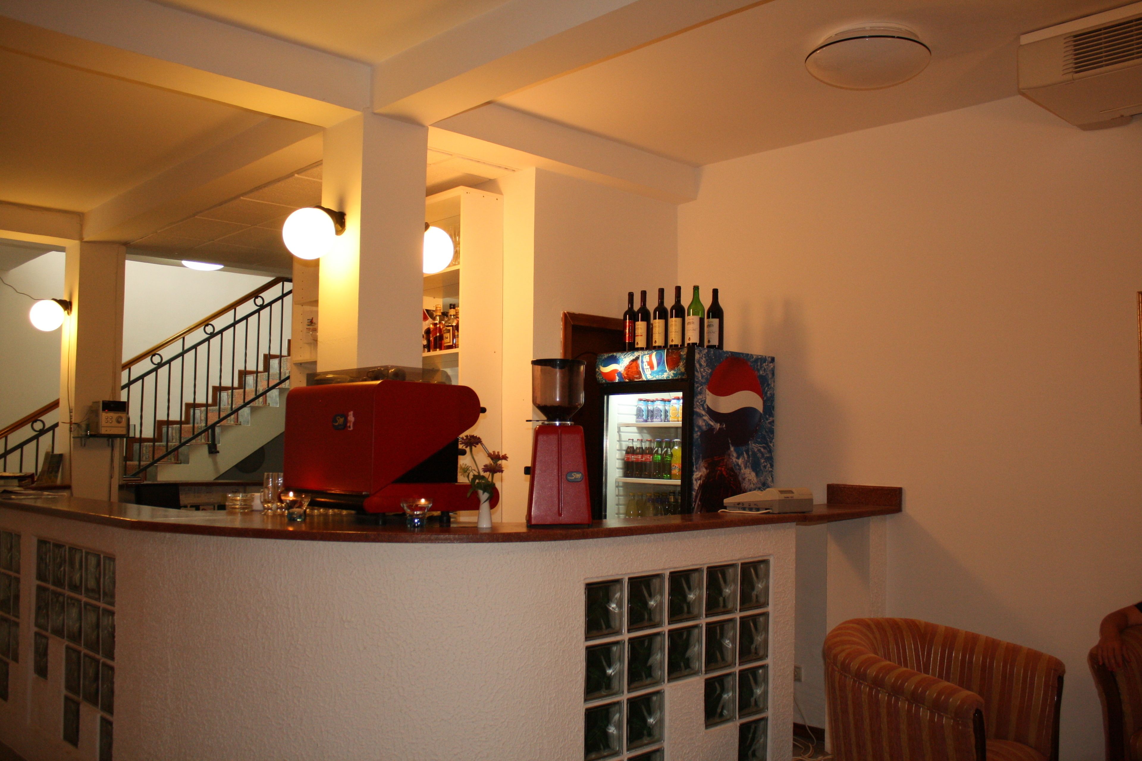 Angolo bar con un frigorifero pieno di bevande, una macchina da caffè e un portabottiglie per vino.