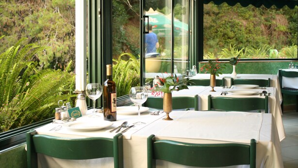 Comedor con mesas dispuestas para dos, con vista a zonas verdes.