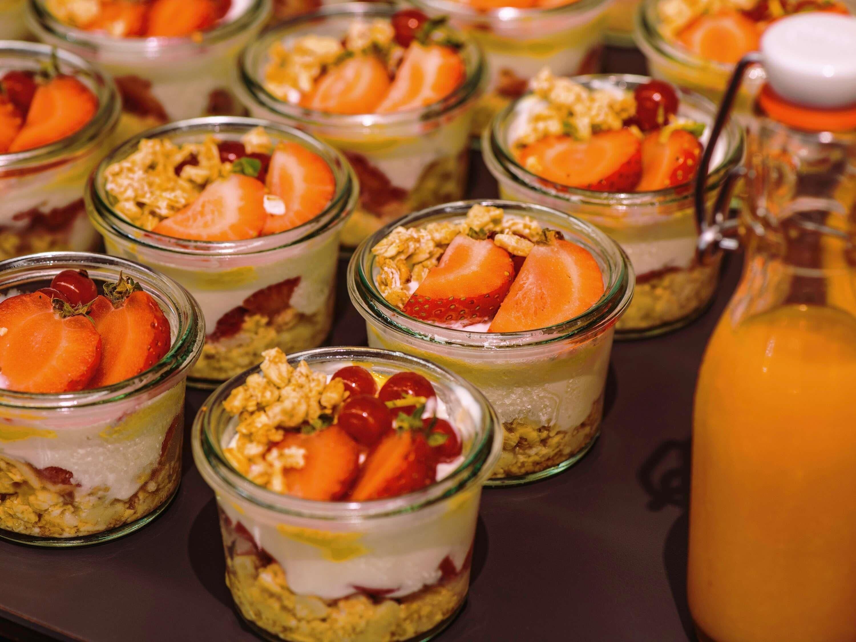 Verschillende gelaagde desserts in glazen bekers, waarvan sommige belegd zijn met fruit en granola.
