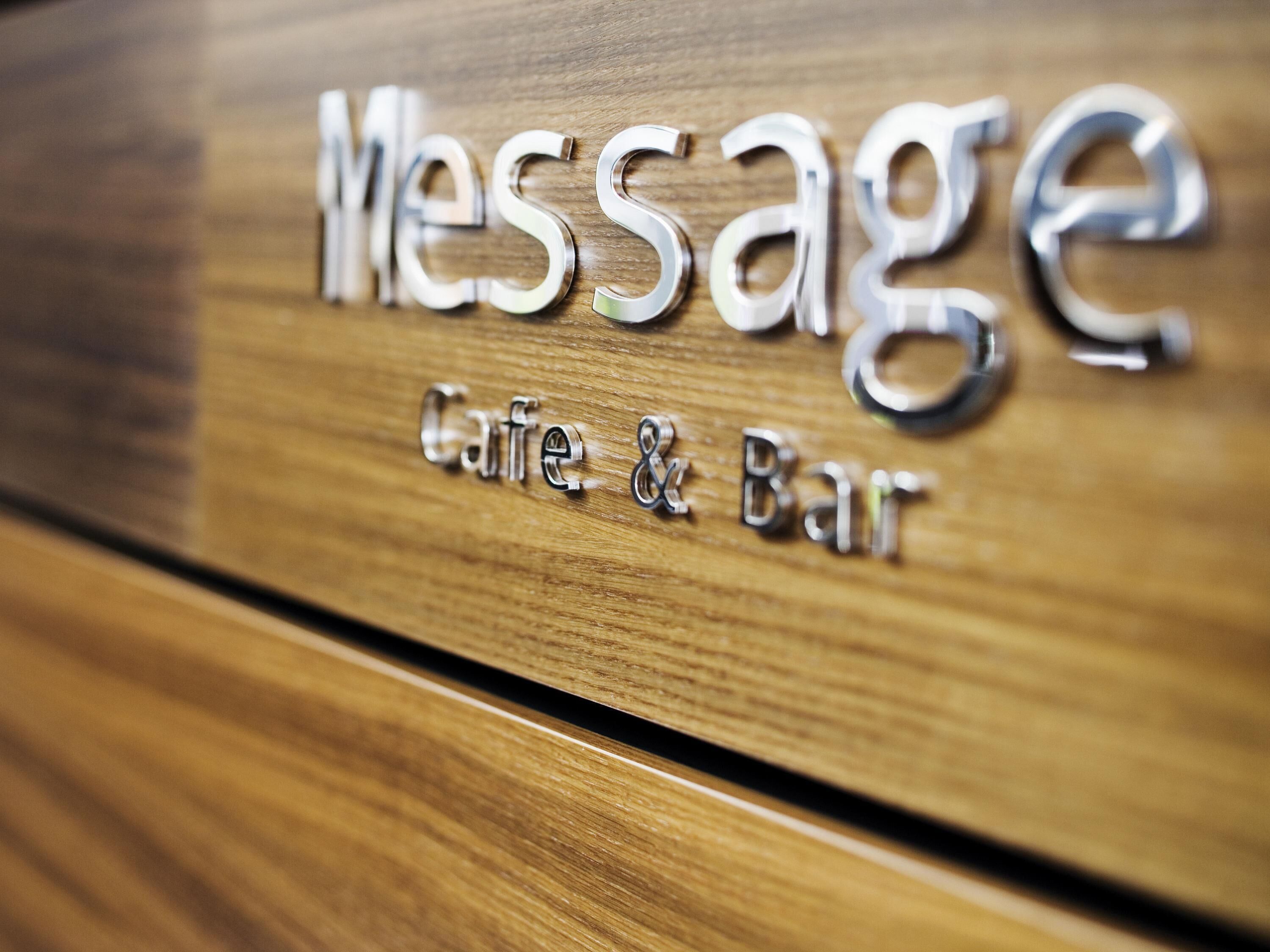 Eine Holzfläche mit der eingravierten Aufschrift 'Message Cafe & Bar'.