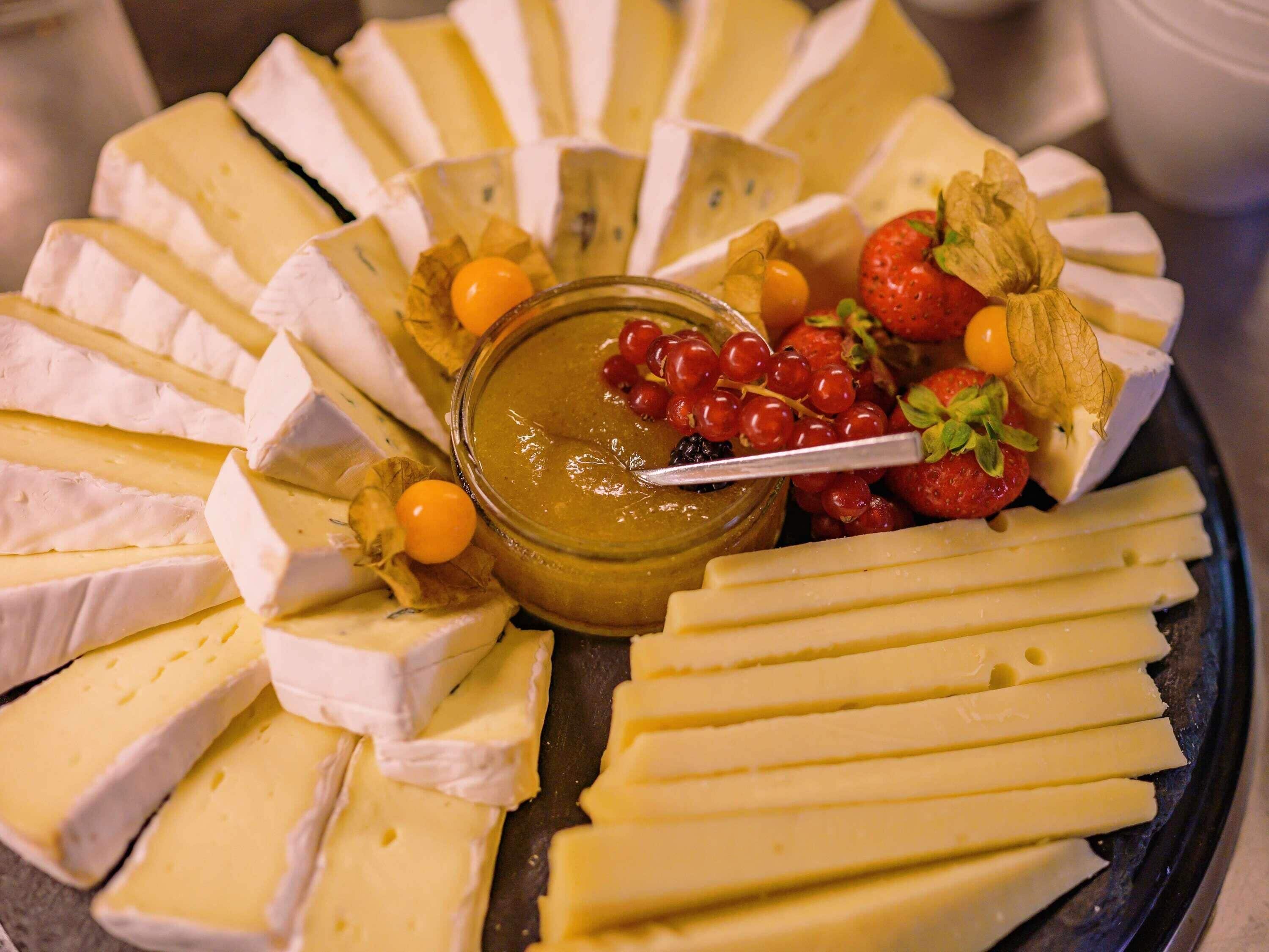 Una tabla de quesos con varios tipos de queso, uvas y fresas.