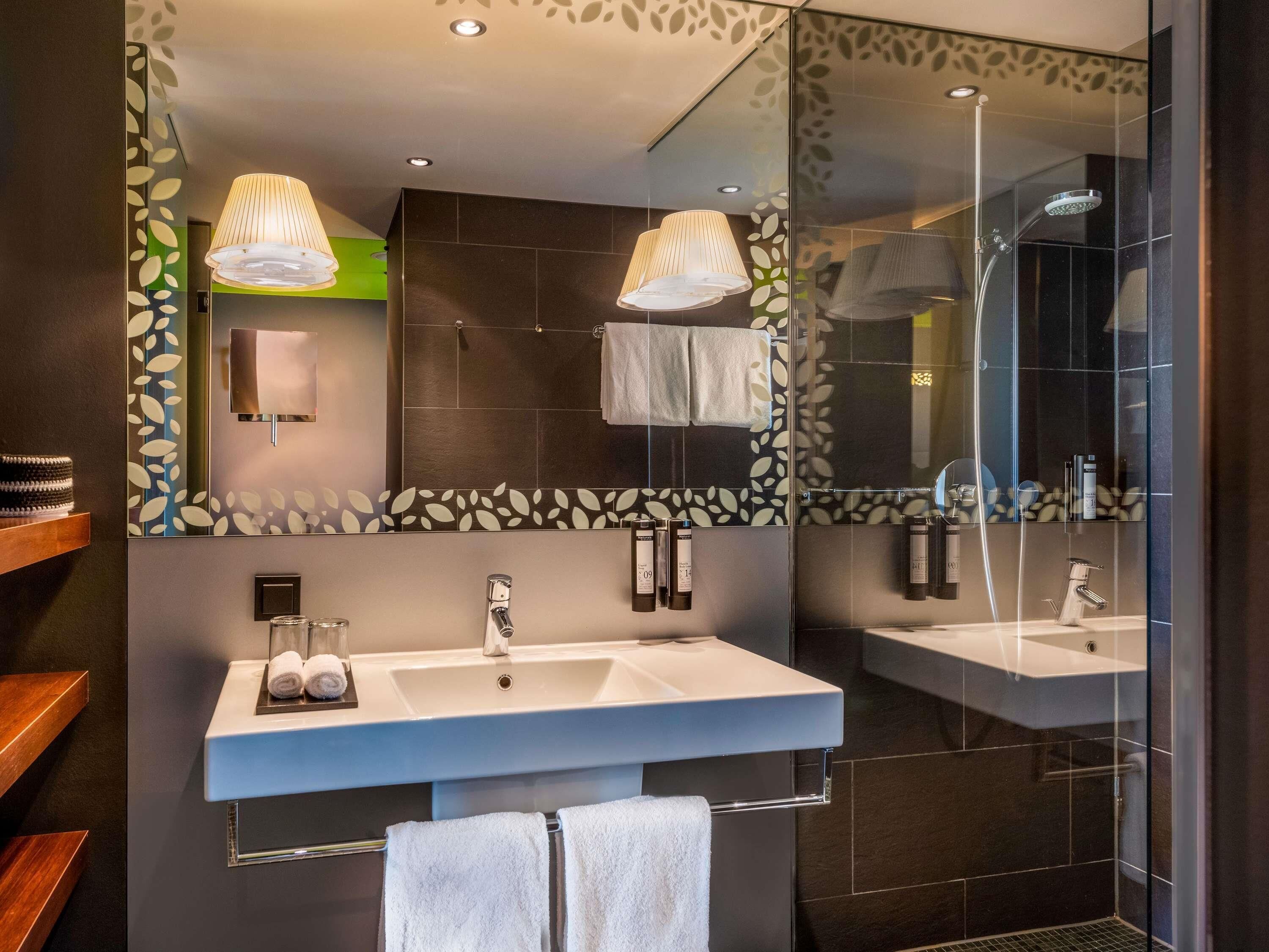 Un baño moderno con dos lavamanos, un espejo grande y una cabina de ducha de vidrio.