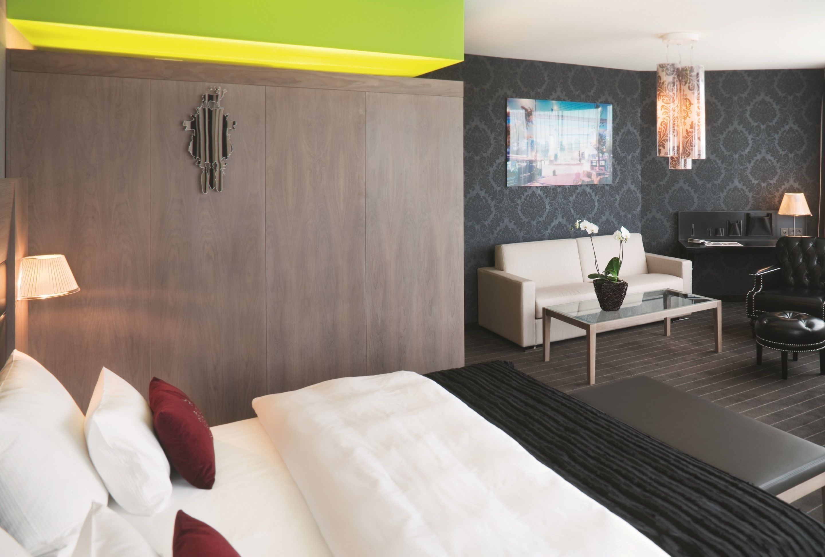 Habitación de hotel moderna con una cama grande, un sofá, una mesa de centro y un escritorio.