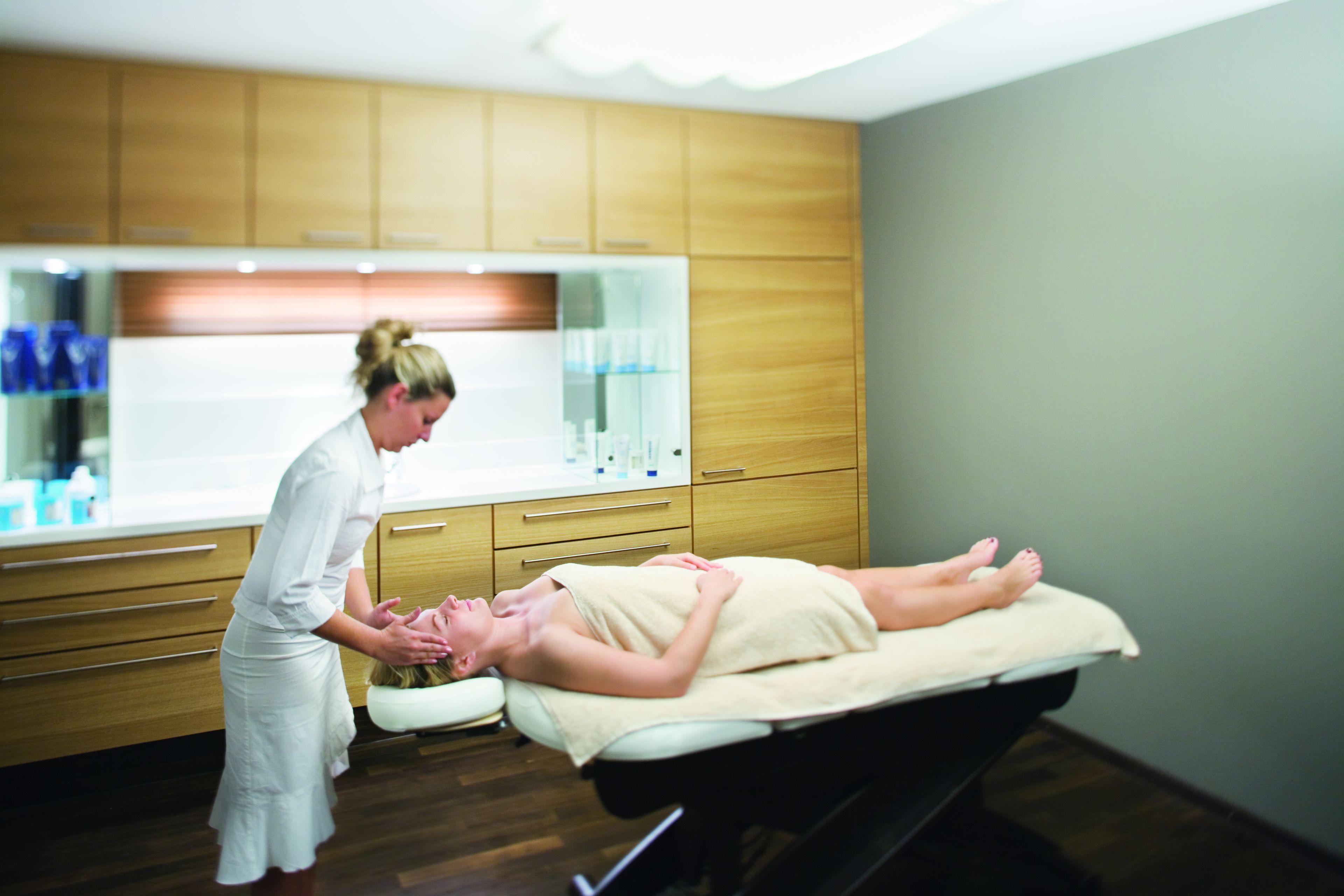 A massage therapy room with wooden cabinets and a massage table.
