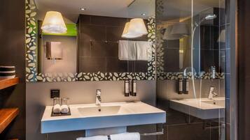 Moderni kylpyhuone, jossa on suuri peili, kaksi pesuallasta ja lasiseinällä varustettu suihku.