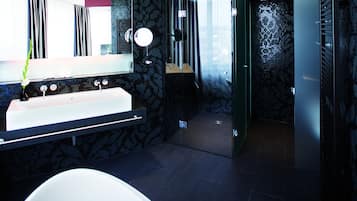 Un baño moderno con un espejo grande, una bañera blanca y un box de ducha de vidrio.