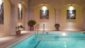 Ein Innenpool mit gefliesten Wänden, Topfpflanzen und Kunstwerken.