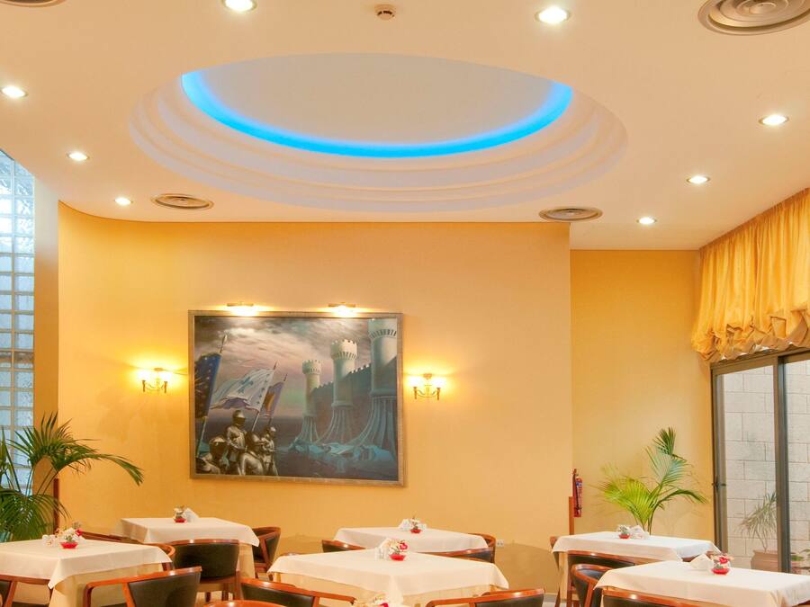 Un comedor con mesas redondas, sillas y un gran cuadro en la pared.