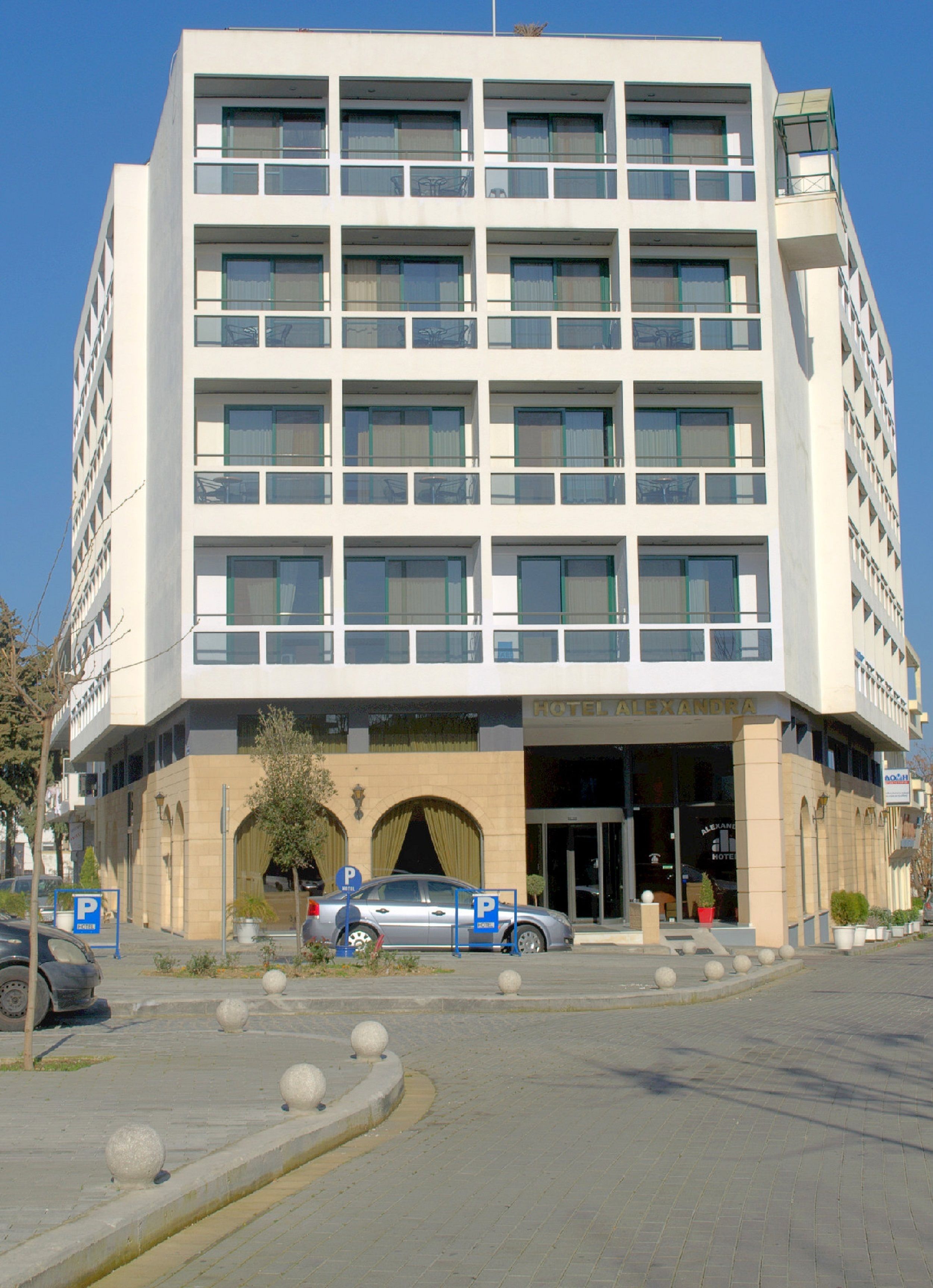 A modern hotel with a symmetrical facade, multiple balconies, and a central entrance.