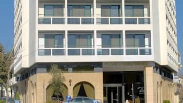 A modern hotel with a symmetrical facade, multiple balconies, and a central entrance.