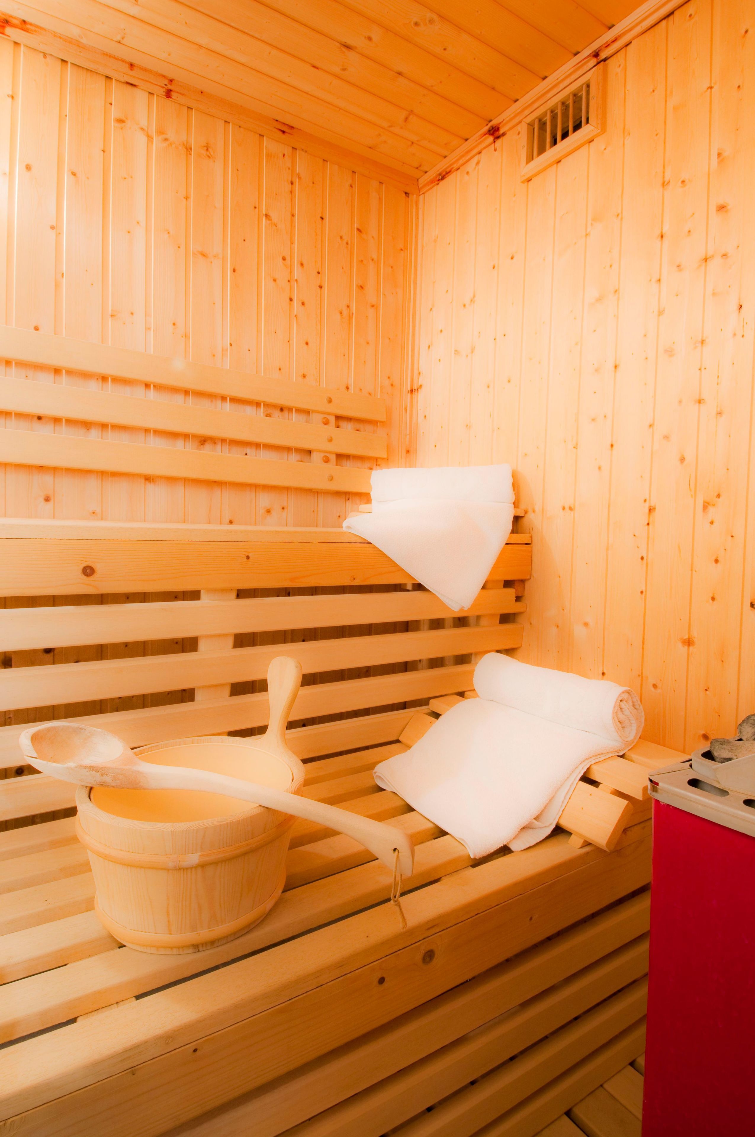 A sauna with wooden benches, a wooden bucket, and a towel.
