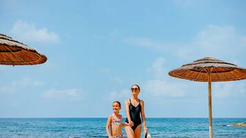 Na praia, espreguiçadeiras, guarda-sóis, toalhas de praia