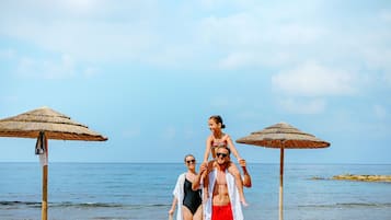 En la playa, sillas reclinables de playa, sombrillas, toallas de playa