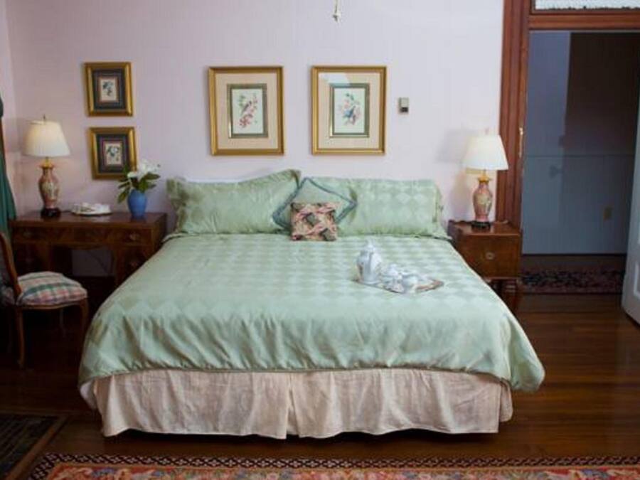 A bedroom with a bed, two bedside tables with lamps, a chair, and a door.