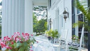 A white porch with white chairs and potted plants. - Lookaway Inn (North Augusta)