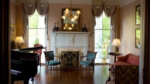 A grand room with a piano, a fireplace, and elegant furniture. - Lookaway Inn (North Augusta)