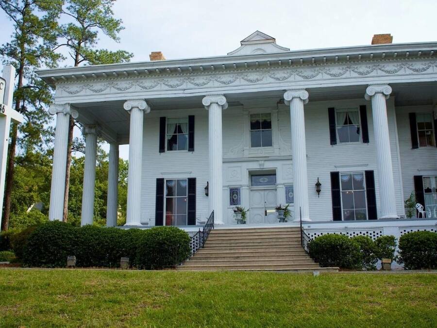 A historic building with a large porch, columns, and a sign indicating it is a historic inn.