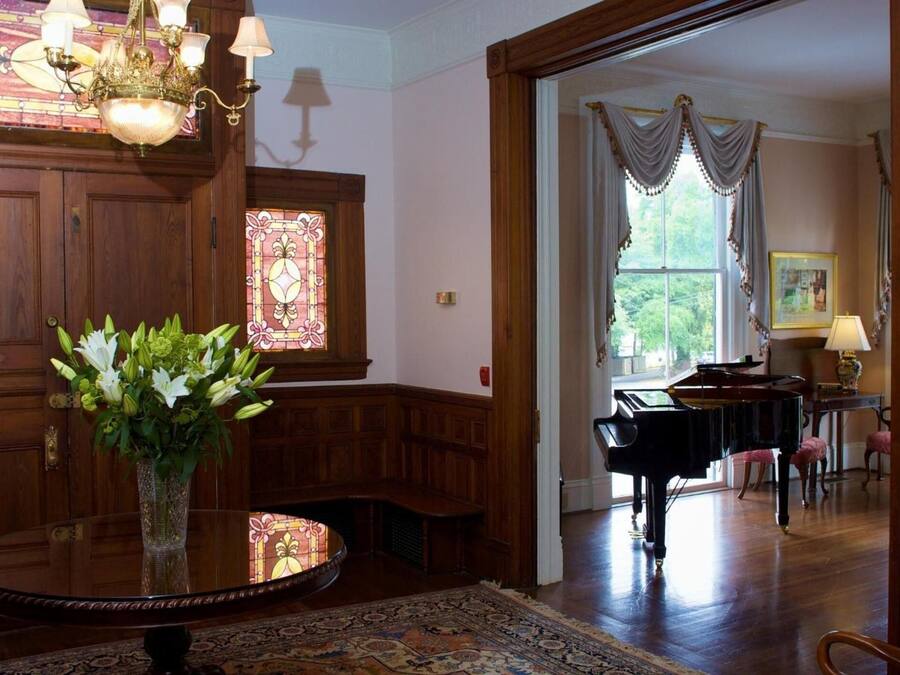A room with a grand piano, a stained glass window, and a wooden bench.