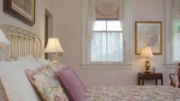 Une chambre à coucher avec un lit, deux tables de chevet, une fenêtre avec des rideaux et un tableau au mur.