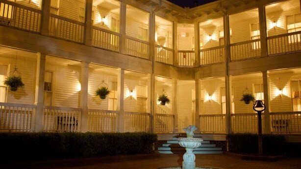 A multi-story hotel with balconies, a central fountain, and hanging plants. - Lookaway Inn (North Augusta)