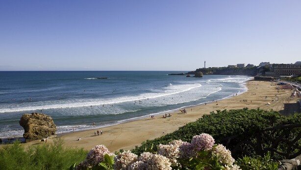 A coastal beach with waves, a lighthouse, and buildings in the background. - ibis Biarritz Anglet Aeroport (Anglet)
