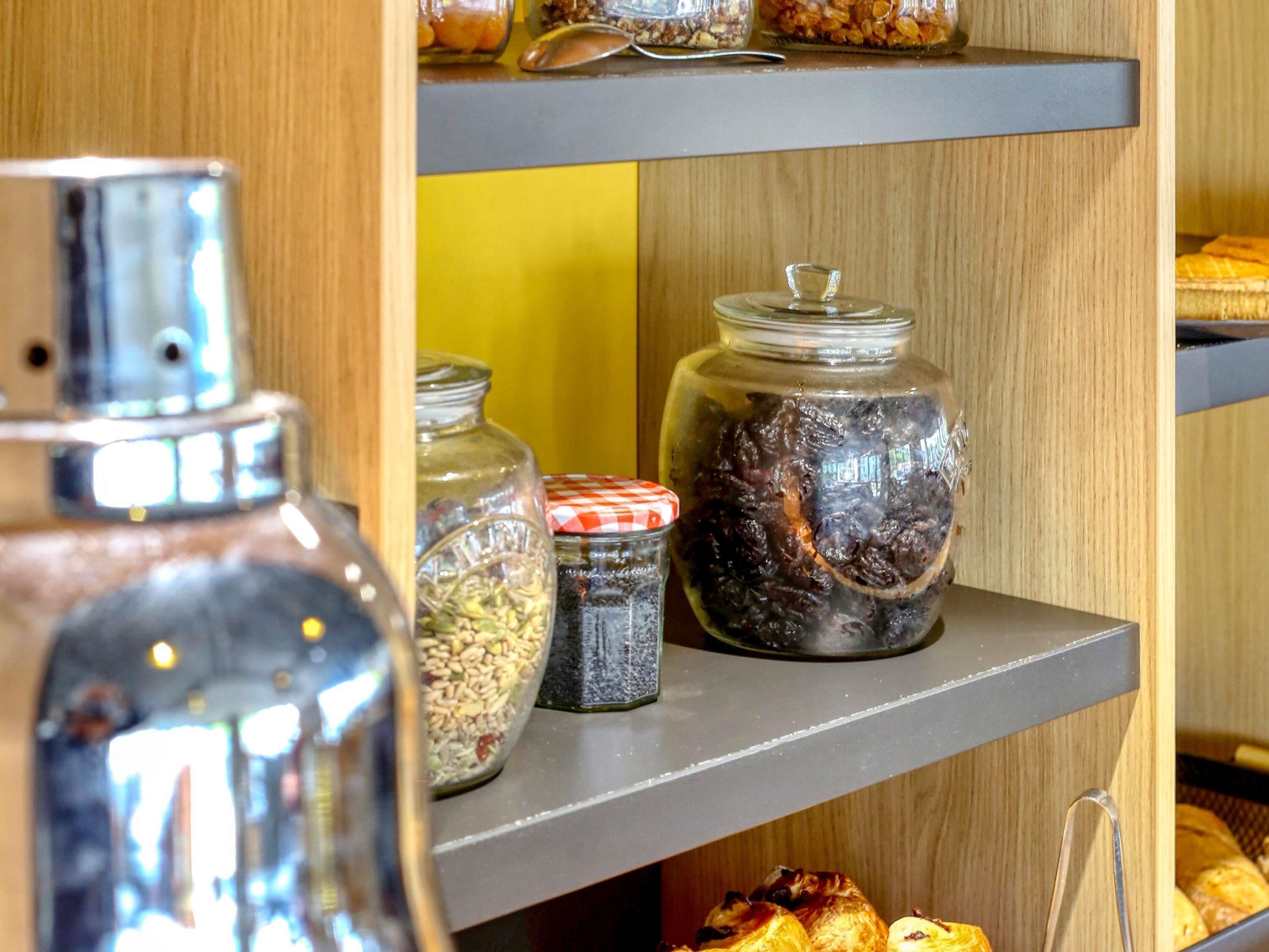 A shelf with jars containing various food items, a metal container, and a loaf of bread.