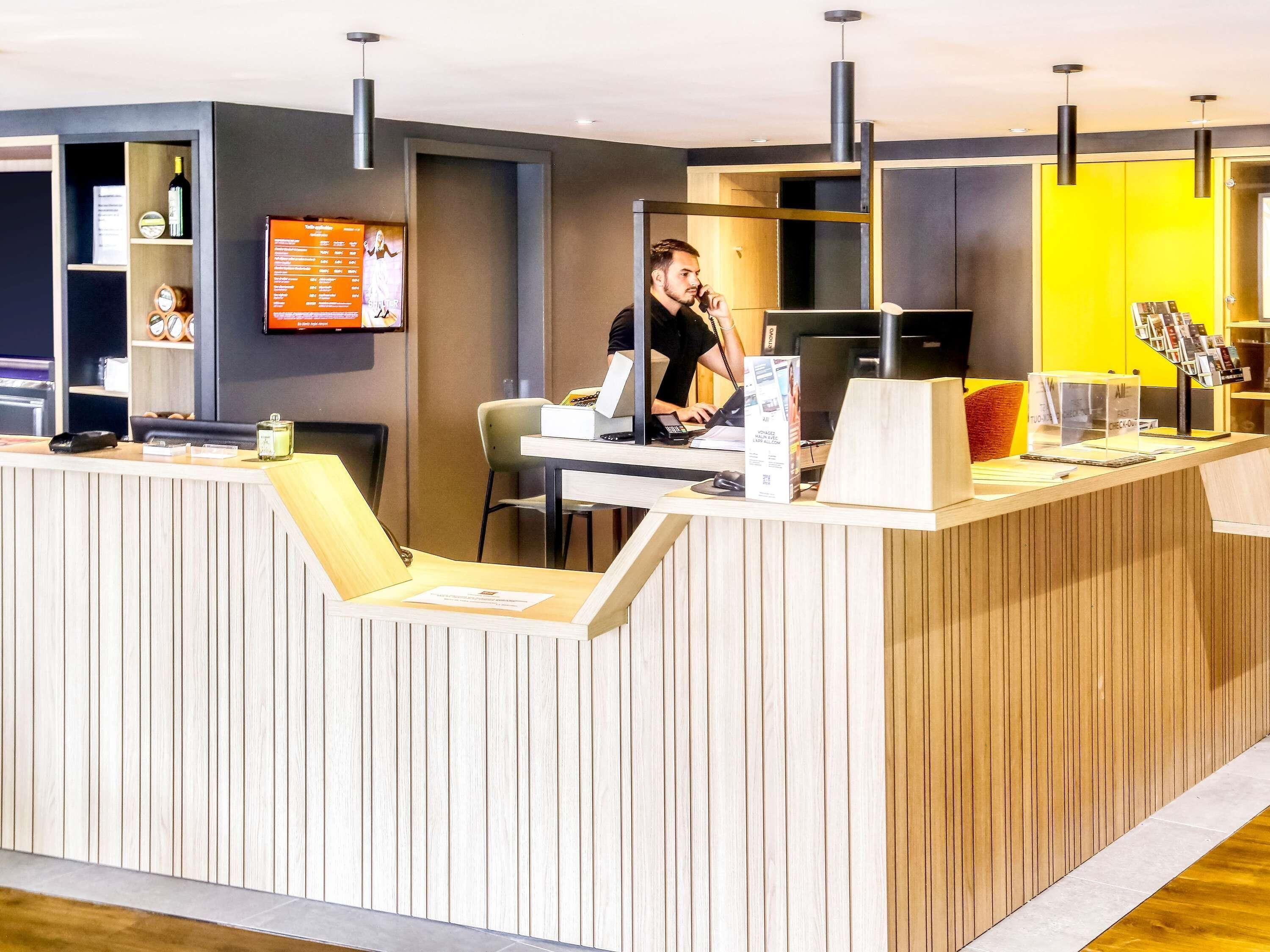 A reception desk with a computer, a phone, and a magazine rack.
