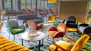 A modern lounge area with various seating options, including sofas and chairs, arranged around tables. - ibis Biarritz Anglet Aeroport (Anglet)