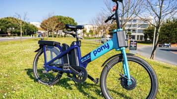 A stationary blue electric bike with 'pony' branding on a grassy area.