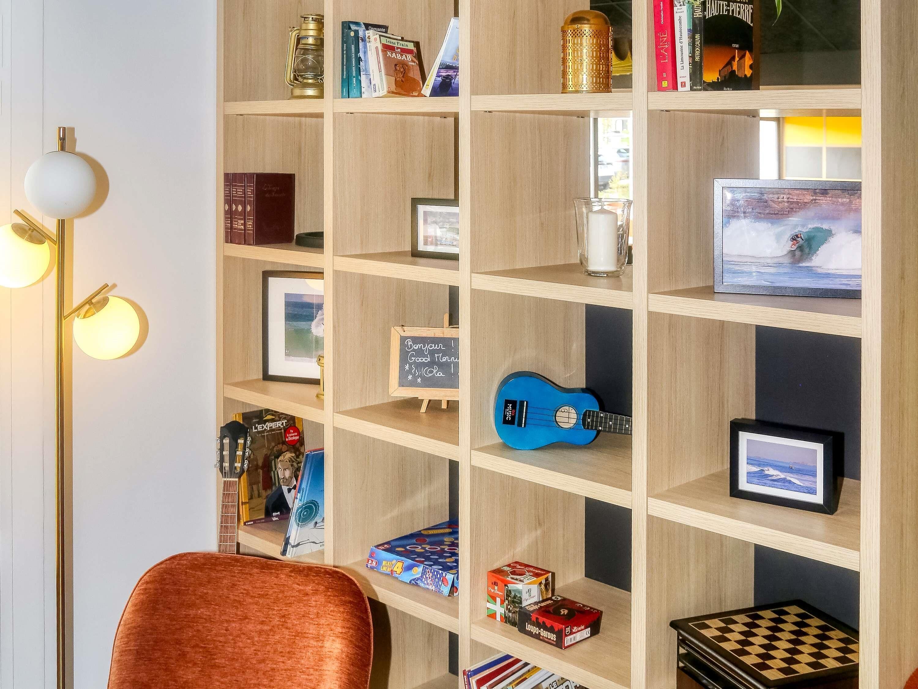 Una habitación con una estantería de madera, un cuadro enmarcado, una guitarra azul y un tablero de ajedrez.