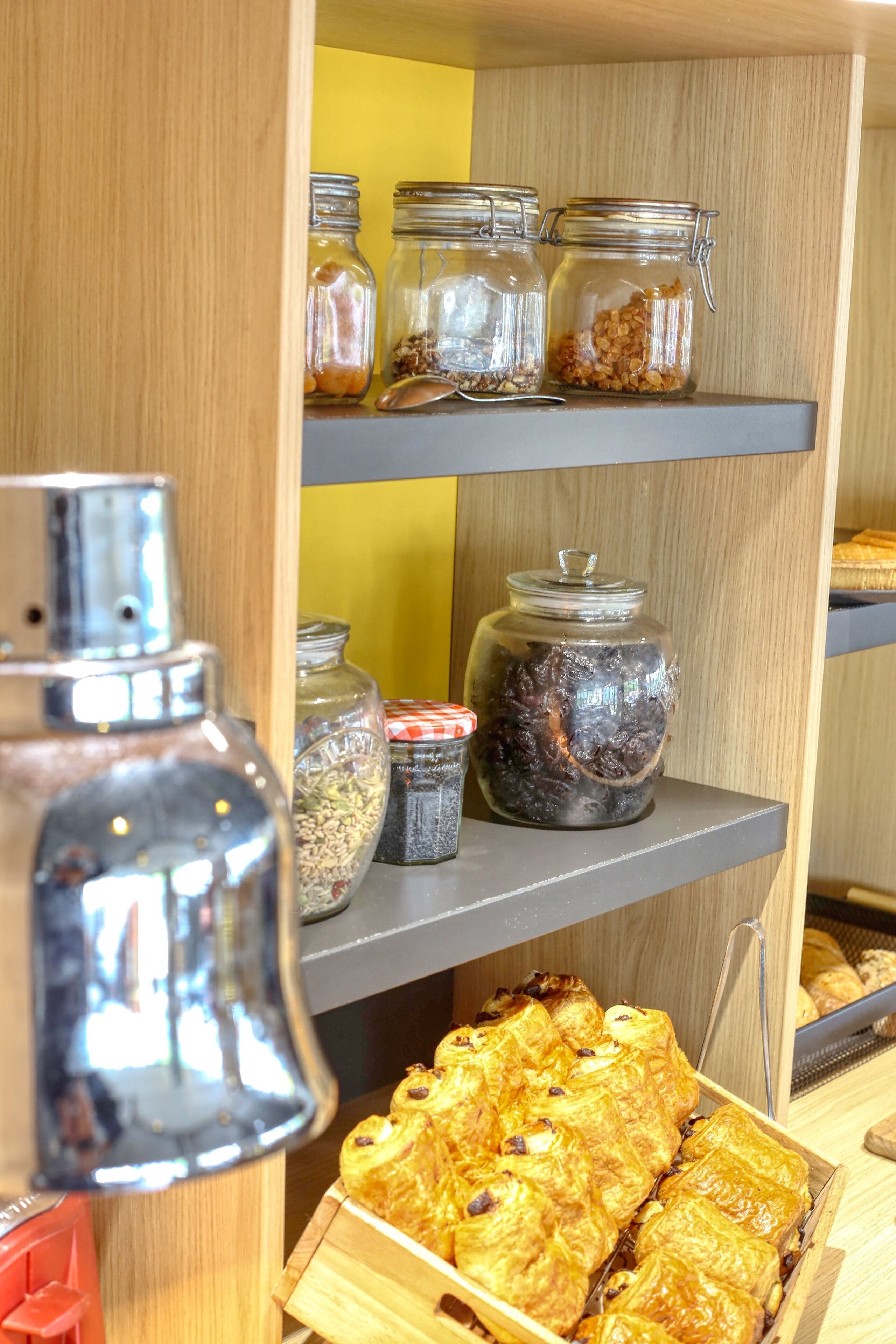 A shelf with jars of spices and a box of pastries.