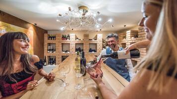 A bar setting with a wooden counter, wine bottles, and glasses.