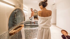 Een moderne spa met een jacuzzi, een houten bank en een glazen wand.