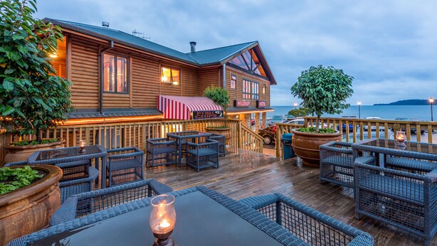 A wooden lodge with a deck, outdoor seating, and a sign reading "Wellesley Hotel."