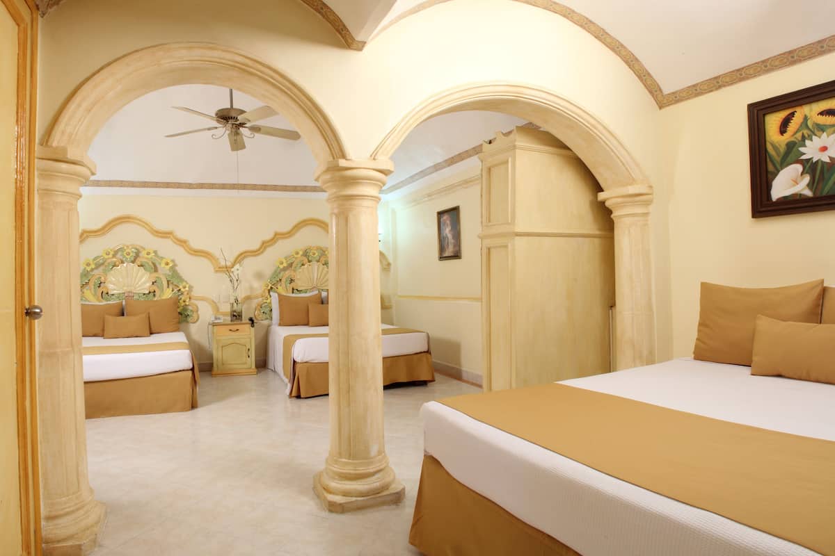 A hotel room with three beds, a ceiling fan, and a painting on the wall.