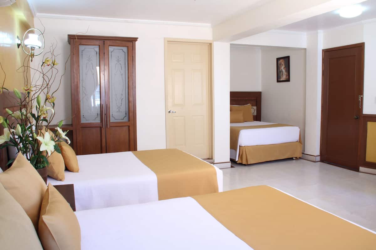 A hotel room with two beds, a wardrobe, and a door leading to another room.
