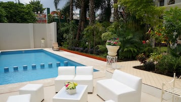 Relax by the serene pool surrounded by lush greenery and comfortable lounge seating.