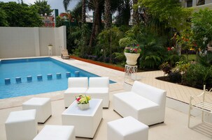 Una piscina al aire libre, sillones reclinables de piscina