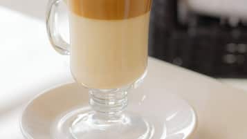 Una taza de café de vidrio transparente con un diseño en capas, sobre un plato blanco.