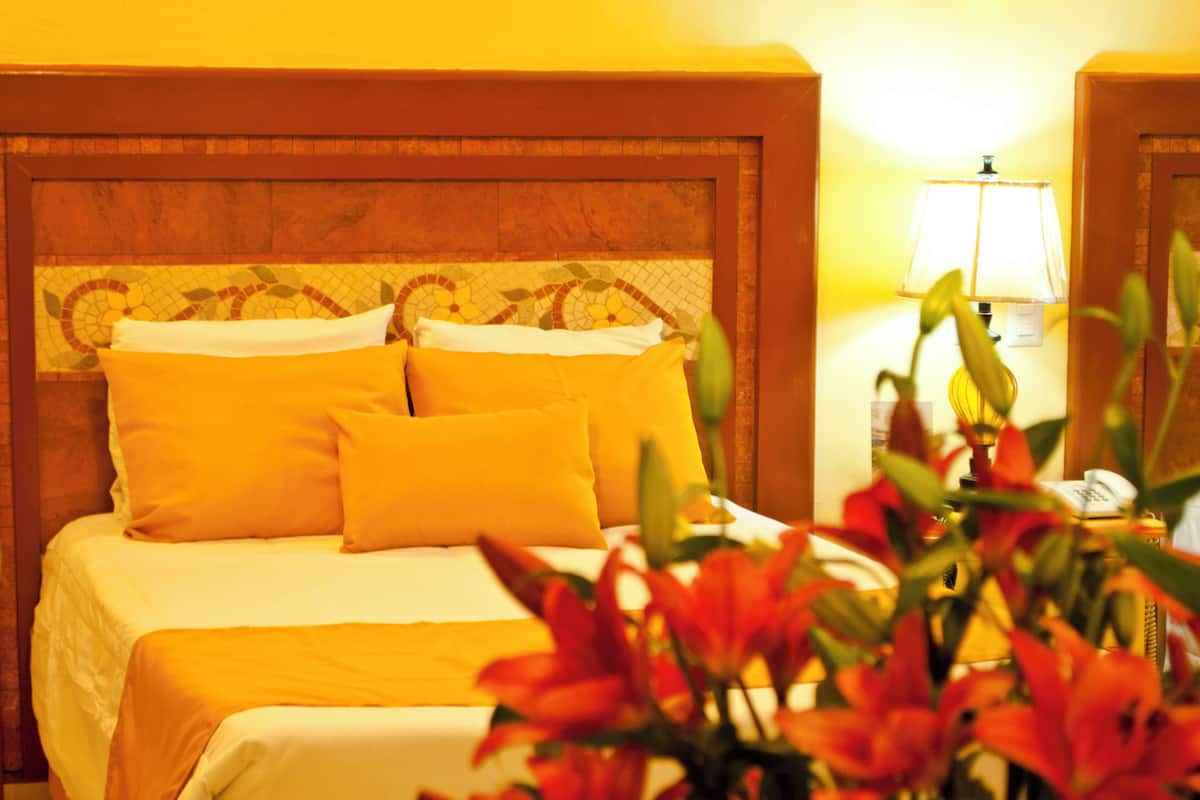A bed with yellow bedding and a headboard with a mosaic pattern.