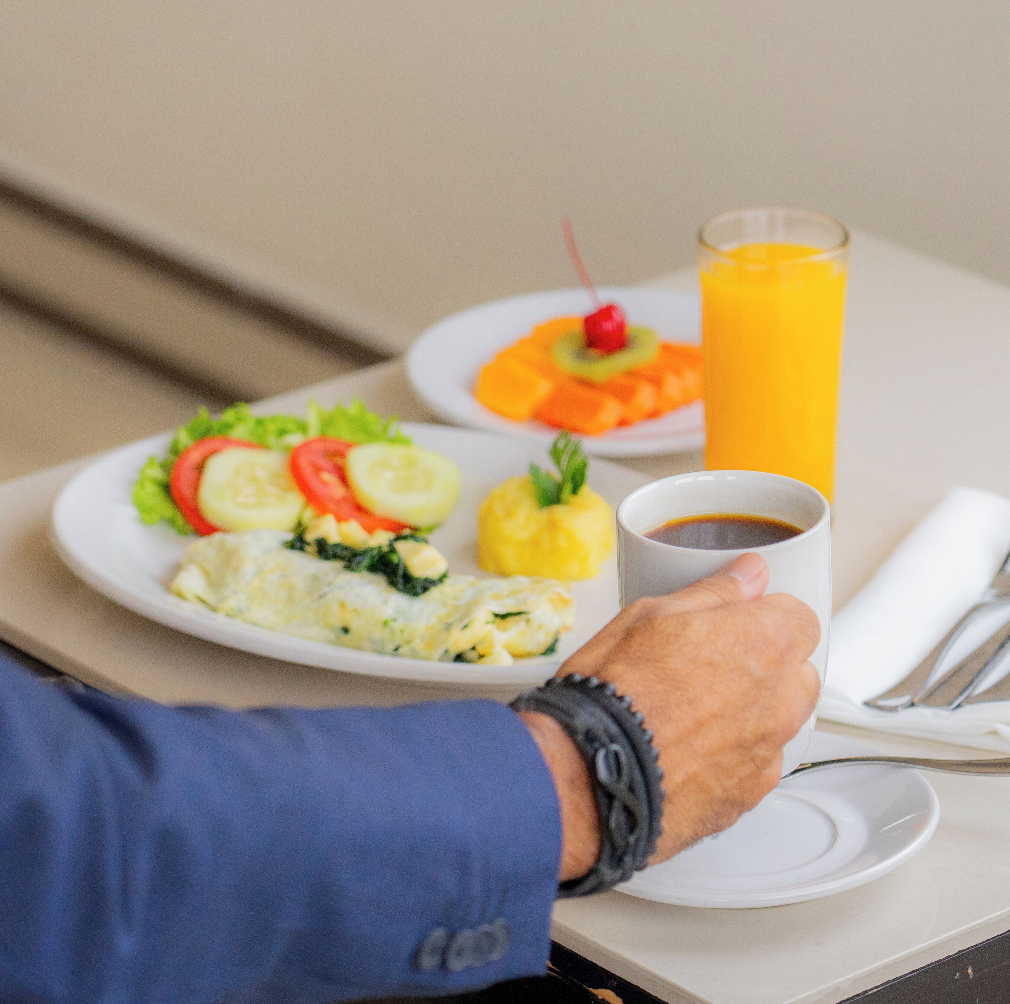 Desayuno con platos de comida, un vaso de jugo de naranja y una taza de café.