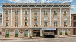 A historic building with a symmetrical facade, multiple windows, and a central entrance with a sign.
