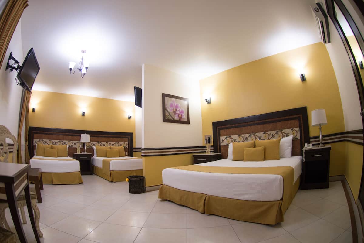 A hotel room with two beds, a TV, a chandelier, and a painting on the wall.