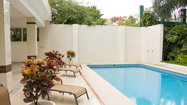 A swimming pool with lounge chairs and potted plants.