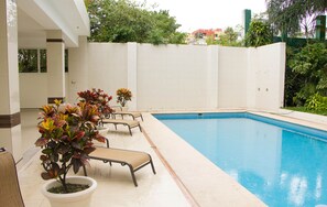 Una piscina con lettini e piante in vaso.