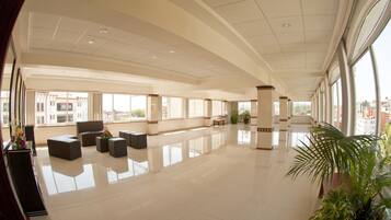 A spacious lobby with a high ceiling, large windows, and a polished floor.