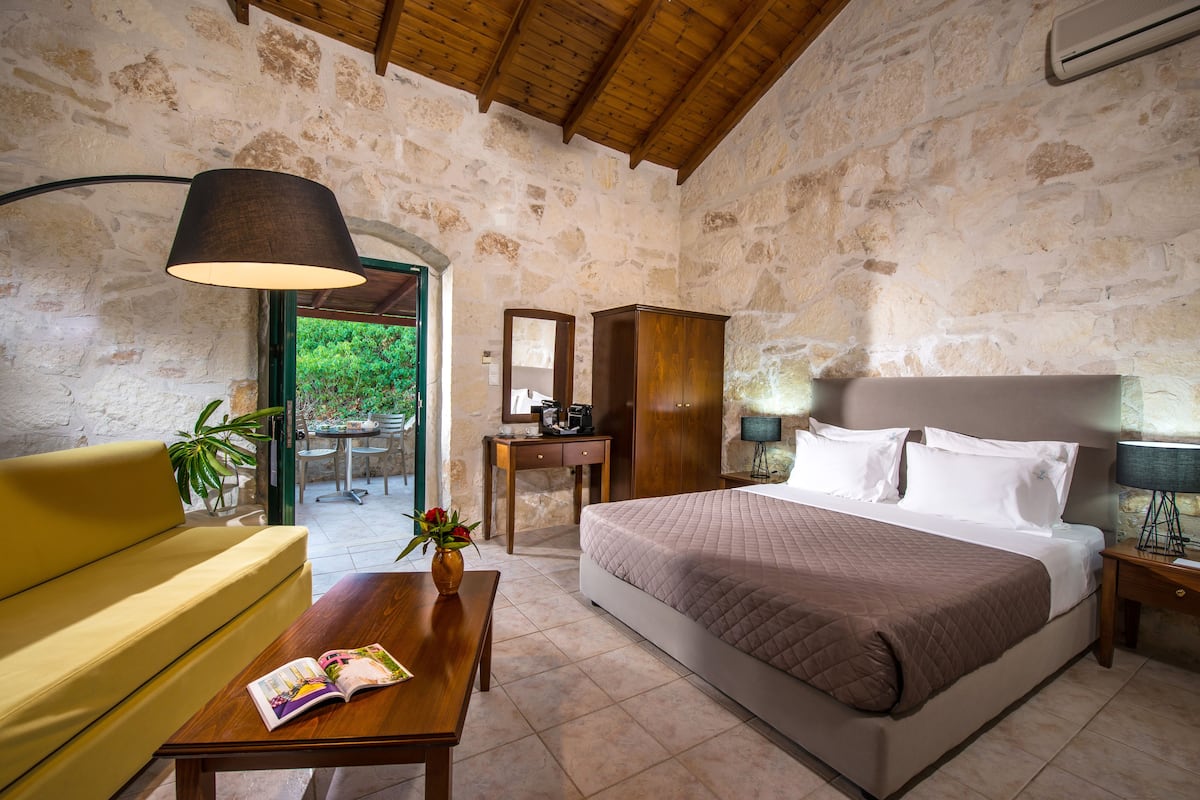 A bedroom with a bed, bedside table, lamp, and a sofa.